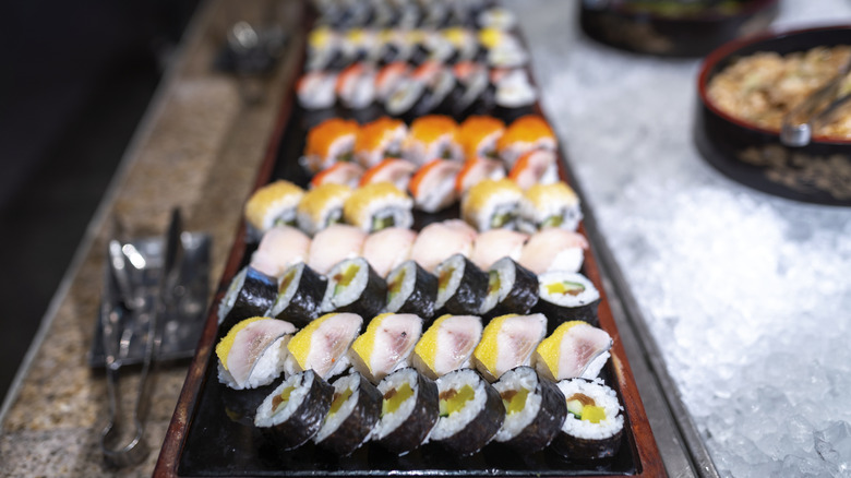 Platters of different types of sushi rolls sitting out at a buffet