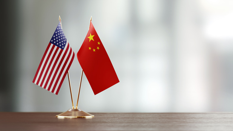 mini-american and chinese flags on a stand on a wooden surface