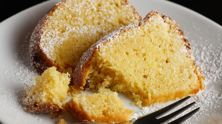 Moist and fluffy yellow cake with icing sugar on a plate.