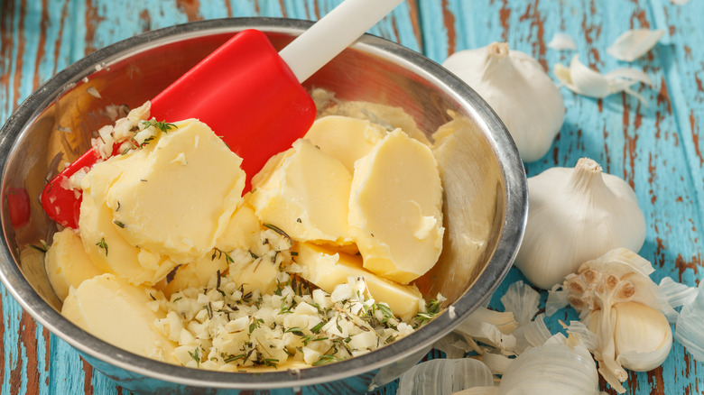 Butter, garlic, and herbs in metal bowl with spatula