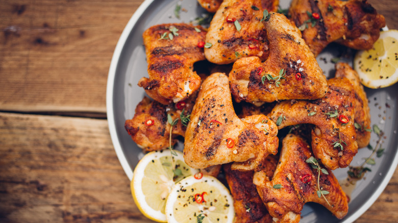 Closeup of plate of chicken wings with herbs and lemon slices