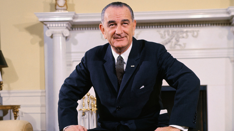 President Lyndon B. Johnson sitting down while wearing a dark suit.