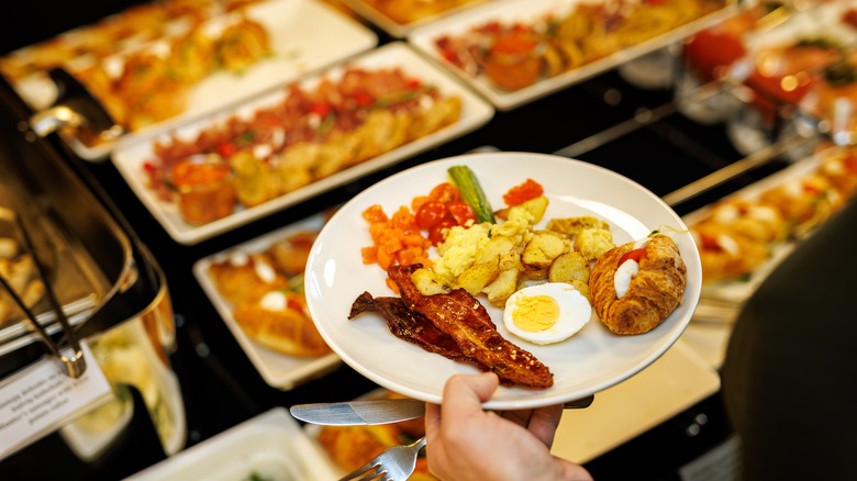 A plate with eggs, hashbrowns, a croissant, and bacon