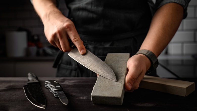 Man sharpening a knife with sharpen stone tool.