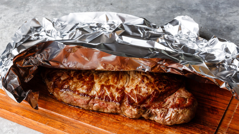 grilled steak resting under foil