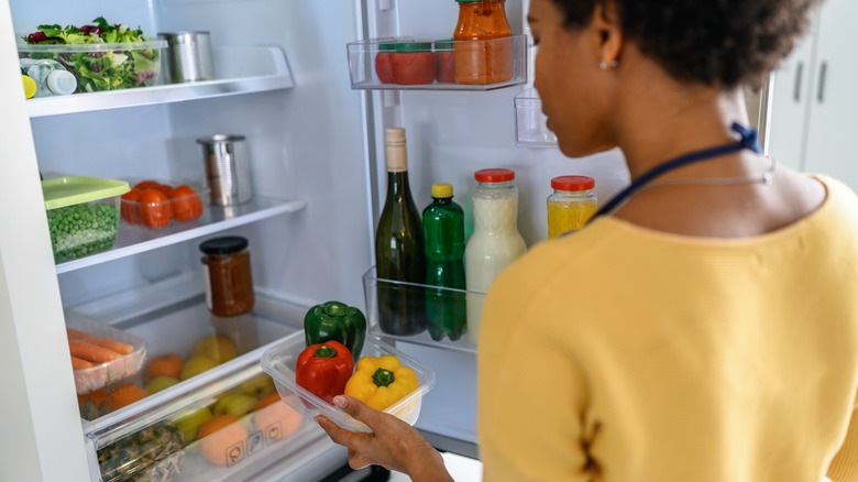 woman pulling produce from the fridge