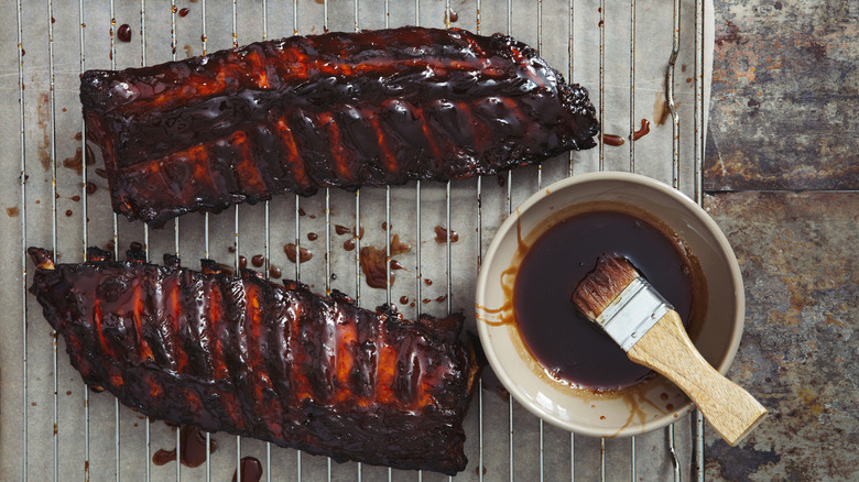 Barbecue sauce in a bowl next to ribs.