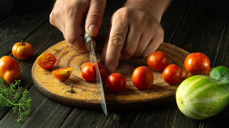 cutting cherry tomatoes on natural cutting board