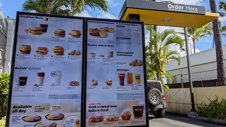 Drive-thru menu with palm trees surrounding it