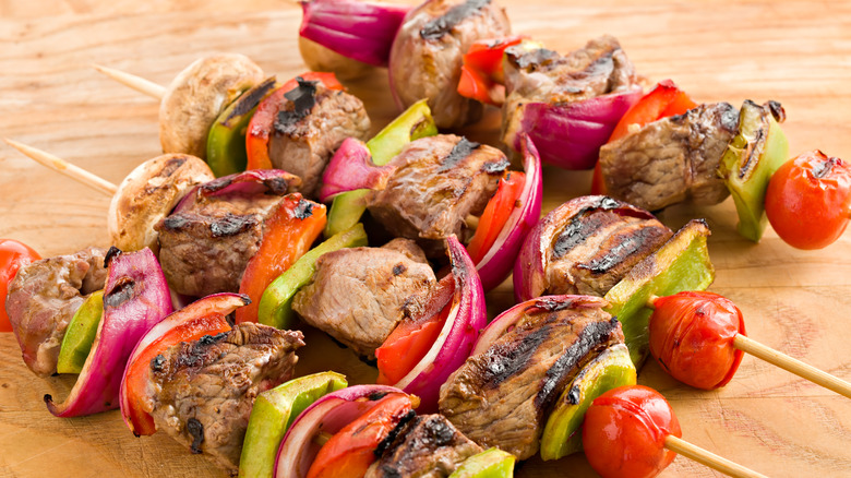 Meat and veggie shish kabobs on a wood platter