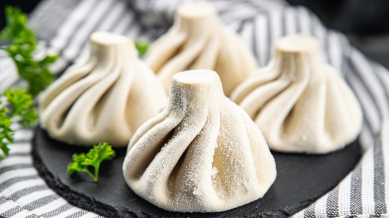 Raw frozen dumplings on black plate