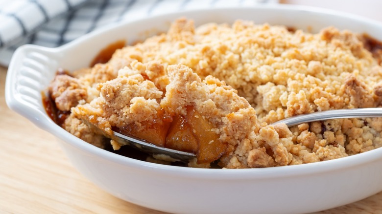 spoon digging into a baking filled with an apple crumble