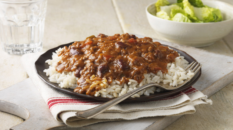 Plate of chili over a bed of white rice on a black plate