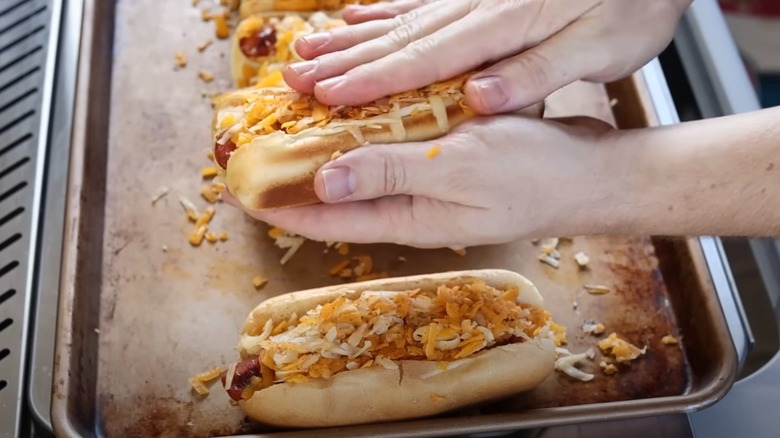 putting shredded cheese on a hot dog