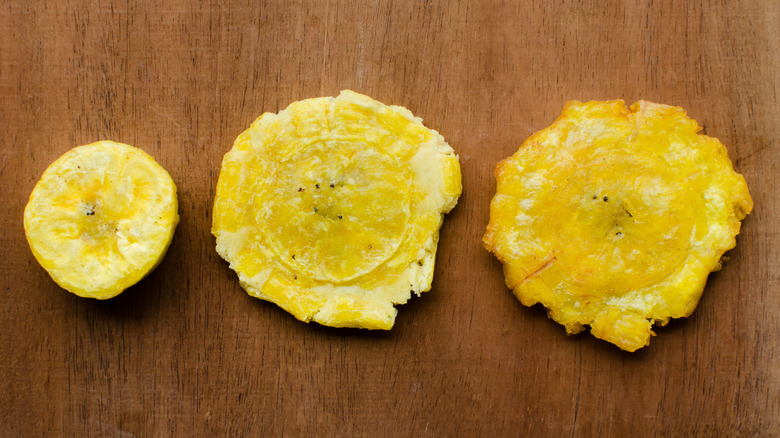 three stages of making tostones, starting with fried plantain slice, flattened plantain, and refried tostones