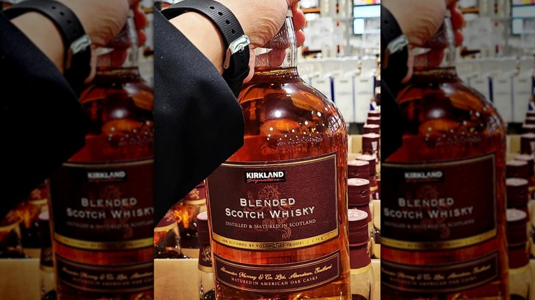 Hand grabbing bottle of Kirkland Signature whisky