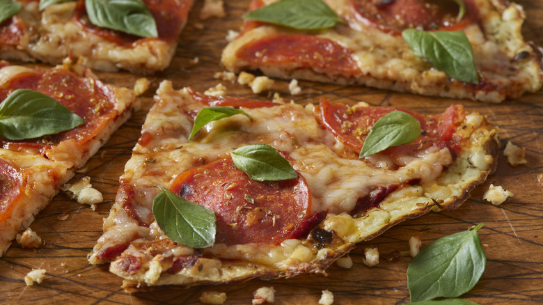 A thin crust pizza topped with pepperoni and basil