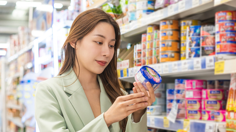 Supermarket shopper examining can of tuna