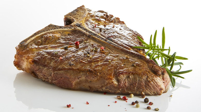 t-bone steak with herbs on white background