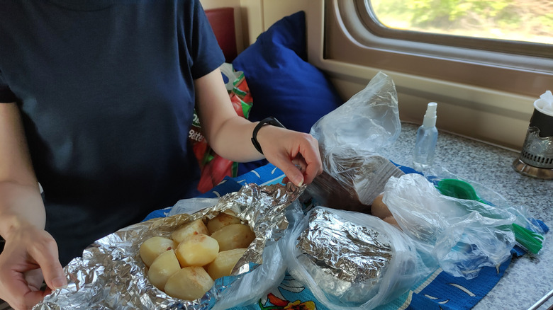 woman with pile of potatoes in foil on a train