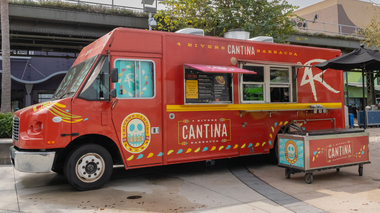 A red, festive food truck parked in front of strip center