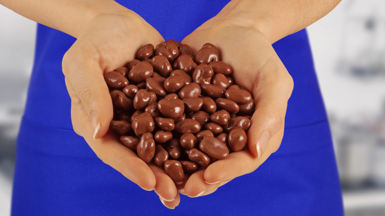 A woman holding Raisinets in her palms.