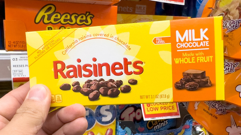 A person holding a packet of Raisinets at a store.