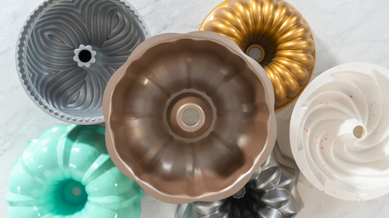 Various Bundt pans placed on a marble counter.