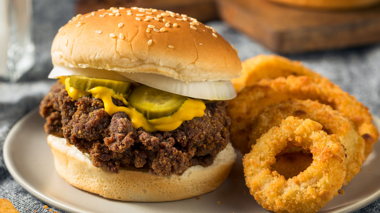 Homemade Mississippi slugburger with onion rings on a white plate.