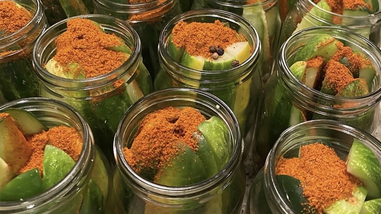 Old Bay seasoning sprinkled into jars of pickles