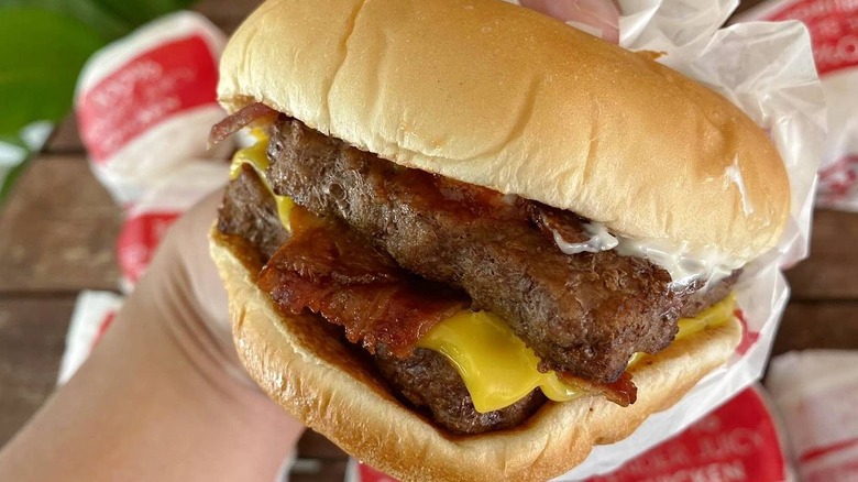 Close-up of hand holding Wendy's Baconator burger