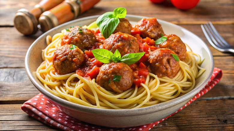 A bowl of spaghetti and meatballs sitting on a table.