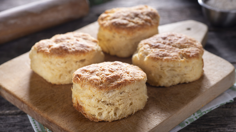 Four large buttermilk biscuits on a wooden try.