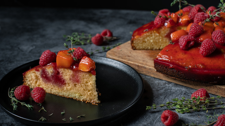 Raspberry rhubarb poke cake topped with raspberries and peaches