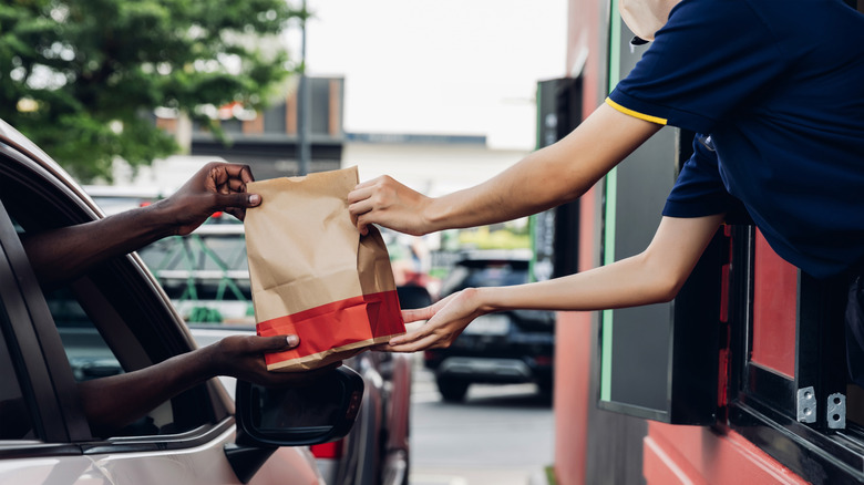 McDonald's drive-thru employee hands a bag to a person in a car