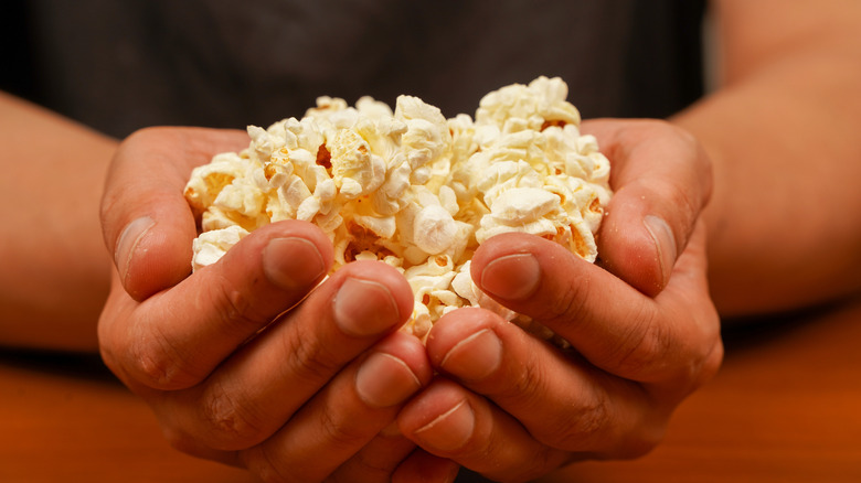 Person's hands holding some popcorn