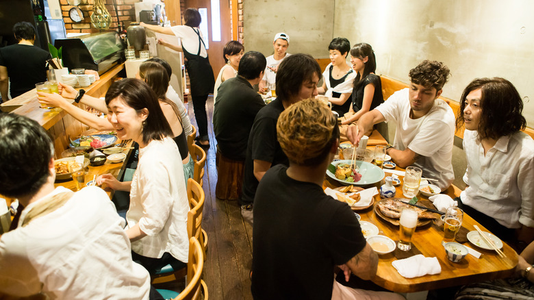 Diners eating in a bustling Japanese restaurant.