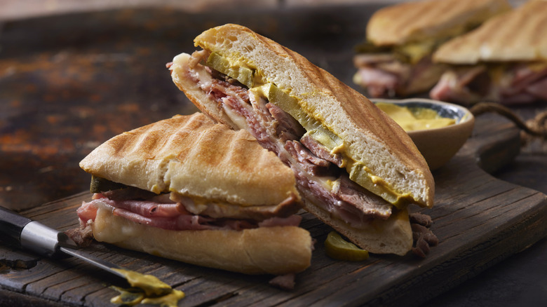 Cuba sandwich cut in half on wood board