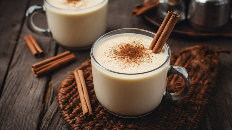 eggnog with nutmeg and a cinnamon stick poking out the top