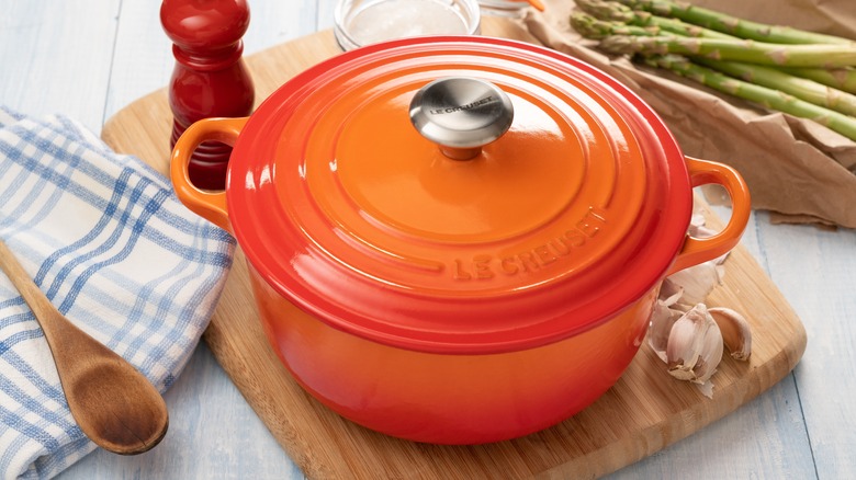 An orange Dutch oven on a cutting board