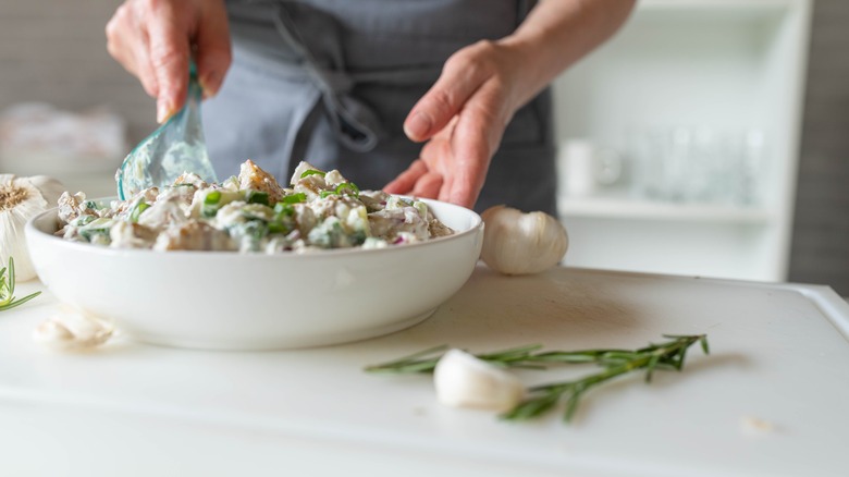 a woman mixing creamy potato salad