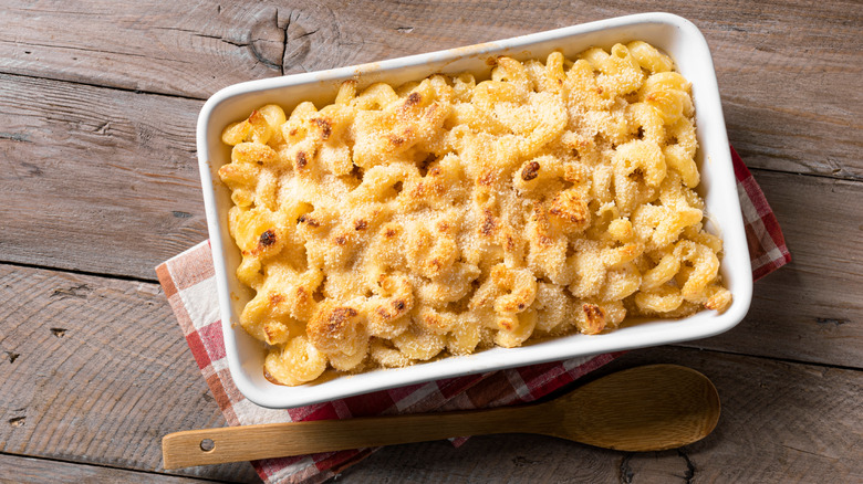 Baked macaroni and cheese with a breadcrumb topping, on a red and white dish towel