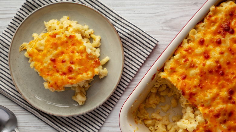 Plate of baked macaroni and cheese with a crispy topping alongside the remaining baked dish