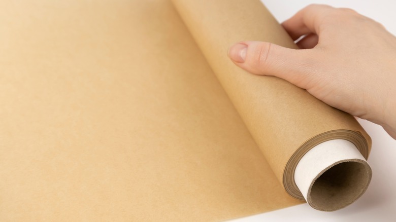 Person unrolling parchment paper