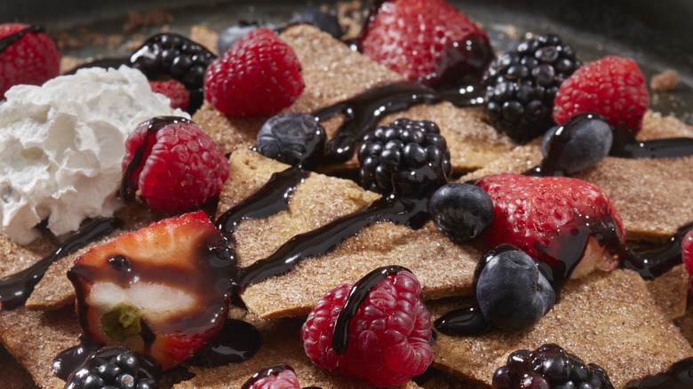 Dessert nachos with blackberries, rasperries, blueberries, chopped strawberries, whipped cream, and chocolate sauce