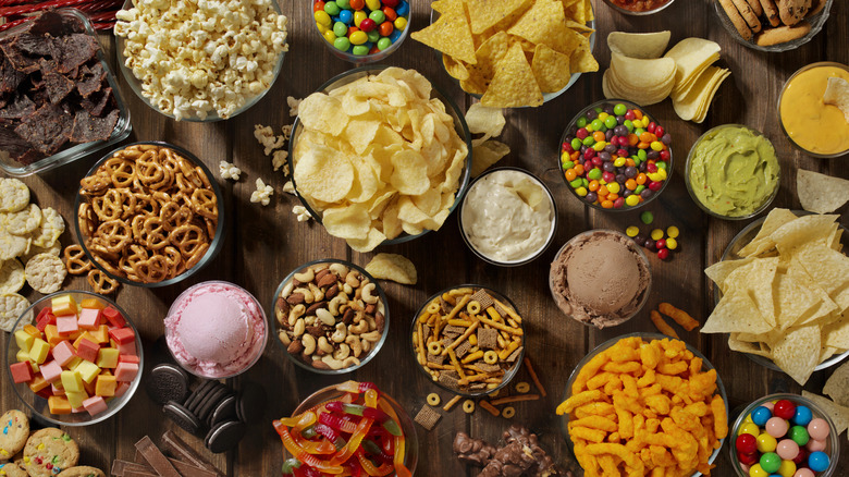 An assortment of salty and sweet snacks like popcorn, chocolate, ice cream, and salted nuts