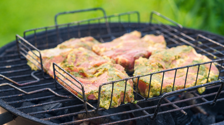 Marinated chicken in a grill basket over grill