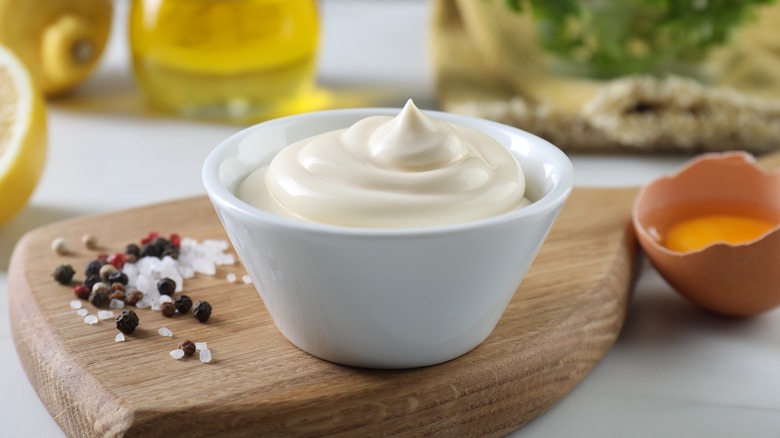 A bowl filled with mayonnaise next to some salt and pepper