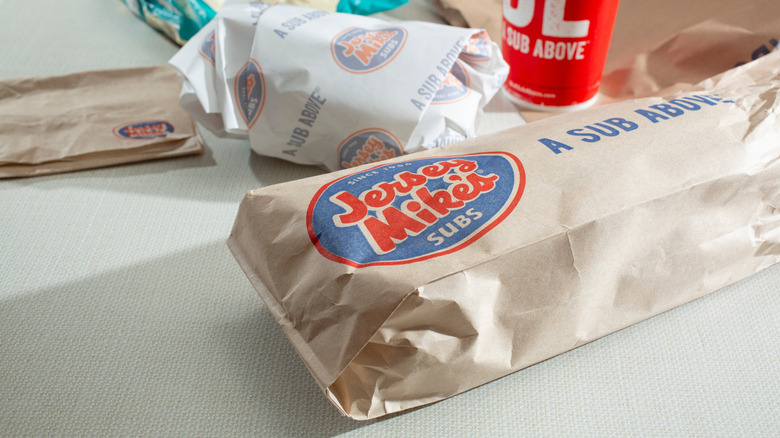 Jersey Mike's subs wrapped and bagged with napkins and a drink