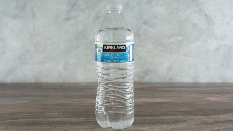 One bottle of Kirkland Signature purified water on a brown surface